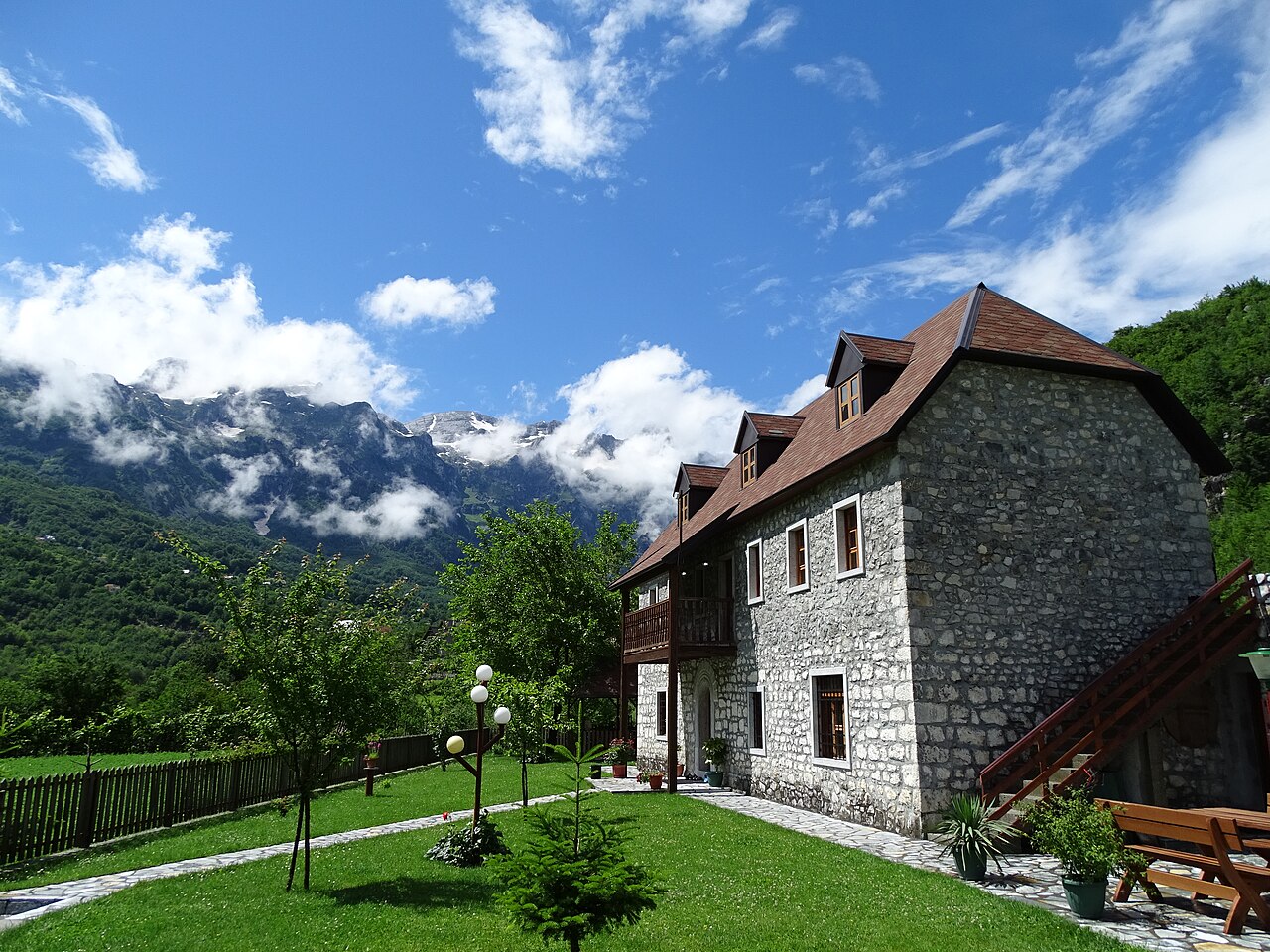 Një bujtinë prej guri në Theth me male në sfond